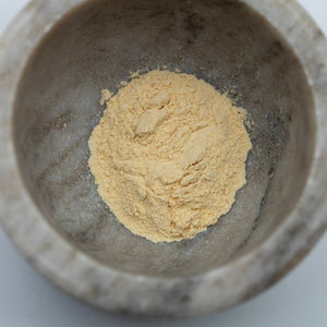 Yellow powder in a stone mortar on a white background