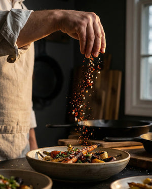 chef with rolled up sleeves using spices