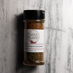 A 3 oz clear plastic spice jar of Casa Flake Chipotle Ranch Seasoning with a black lid and white label, set against a gray marble background.