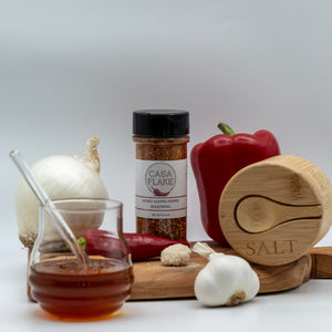 Casa Flake seasoning bottle with a pepper, salt container, and other ingredients on a white background
