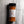 A bottle of Casa Flake Honey Garlic Sriracha seasoning, showing the orange-brown spice powder inside, a white label with the brand logo, and a black cap, set against a gray marble background.
