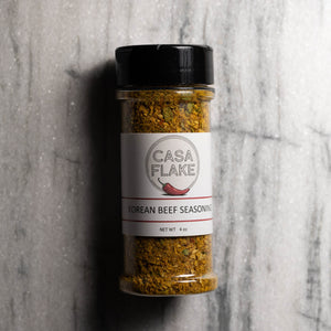 A bottle of Casa Flake Korean Beef Seasoning with a black lid and white label, set against a gray marble background.