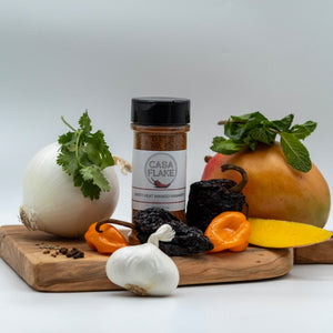 Casa Flake seasoning bottle on a wooden cutting board with various ingredients including a mango, onion, and peppers.