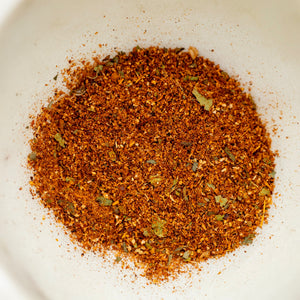 Spice blend with red and green herbs on a white plate
