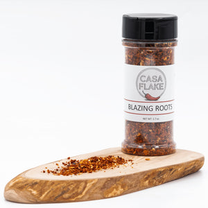Spice jar labeled 'Casa Flake Blazing Roots' on a wooden board with a white background