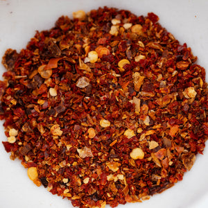 Close-up of Casa Flake Blazing Roots ground red pepper flakes on a white background